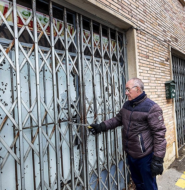 Juan Andrés García examina el candado con el que está cerrado este antiguo supermercado.