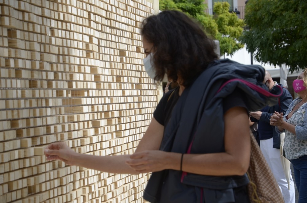 Una mujer retira uno de los bloques con una cita , abriendo el muro
