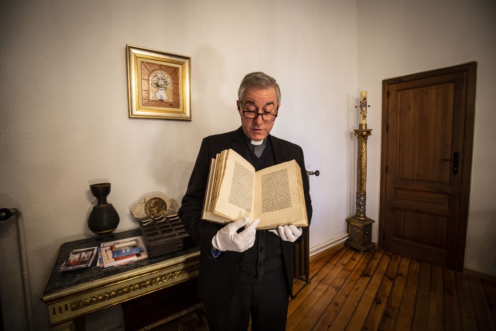 El canónigo archivero, con el libro original, el primero en España, que maneja con guantes.