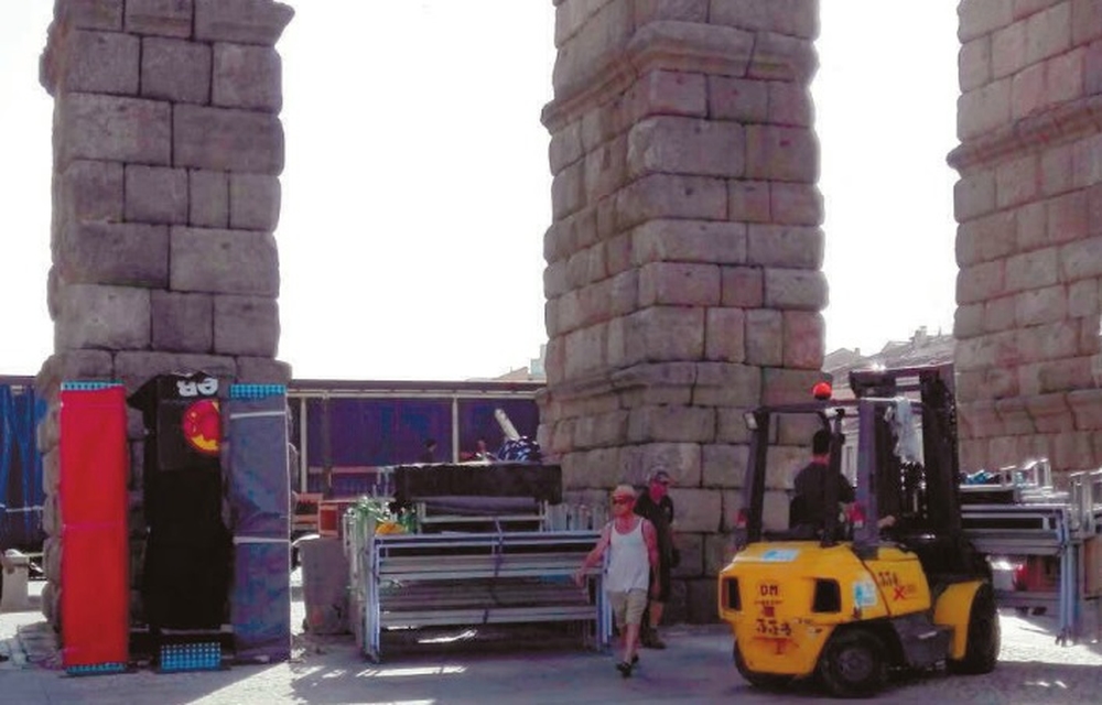 Un dumper manipula estructuras metálicas bajo los arcos del Acueducto durante el montaje de un escenario en el verano de 2017.  / El Día de Segovia