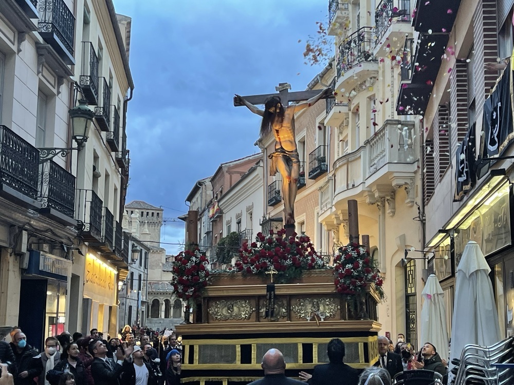 Unos vecinos lanzan al Cristo pétalos de flores a su paso por la Calle Real